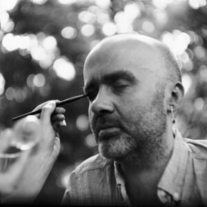 Mann mit geschlossenen Augen, lässt sich von einer Frau schminken